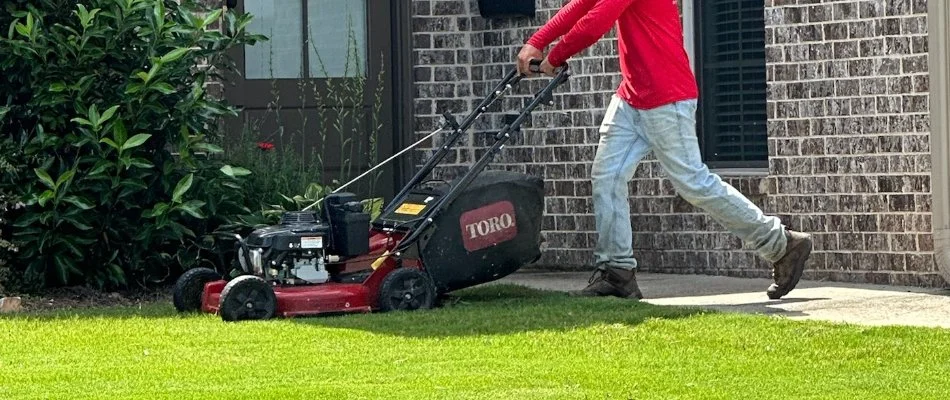 Man pushing a lawn mower across turf in Columbus, GA.