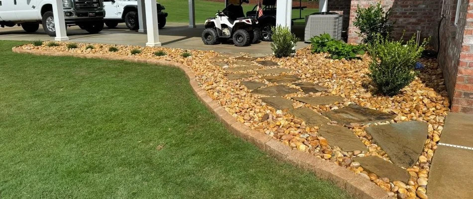 Landscape bed in Columbus, GA, with decorative rocks, walkway, and plants.