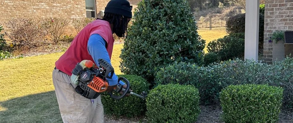 Worker trimming shrubs in Columbus, GA.